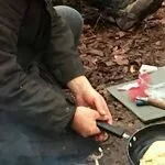 Photo of young person cooking at campfire